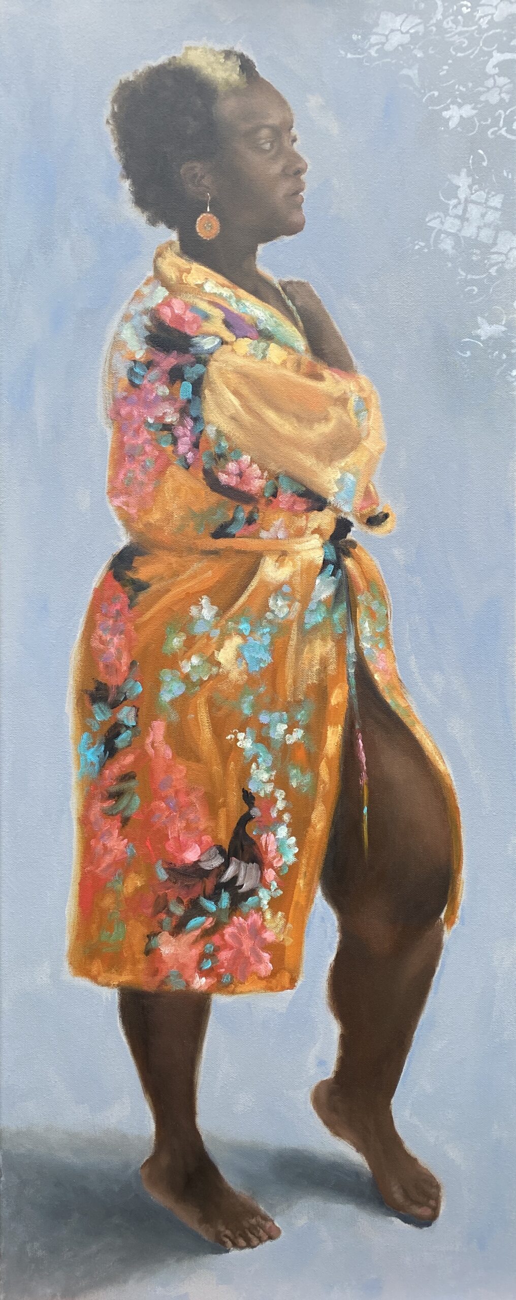 A full length portrait of a young woman wearing an orange satin dressing gown with a colourful floral pattern.